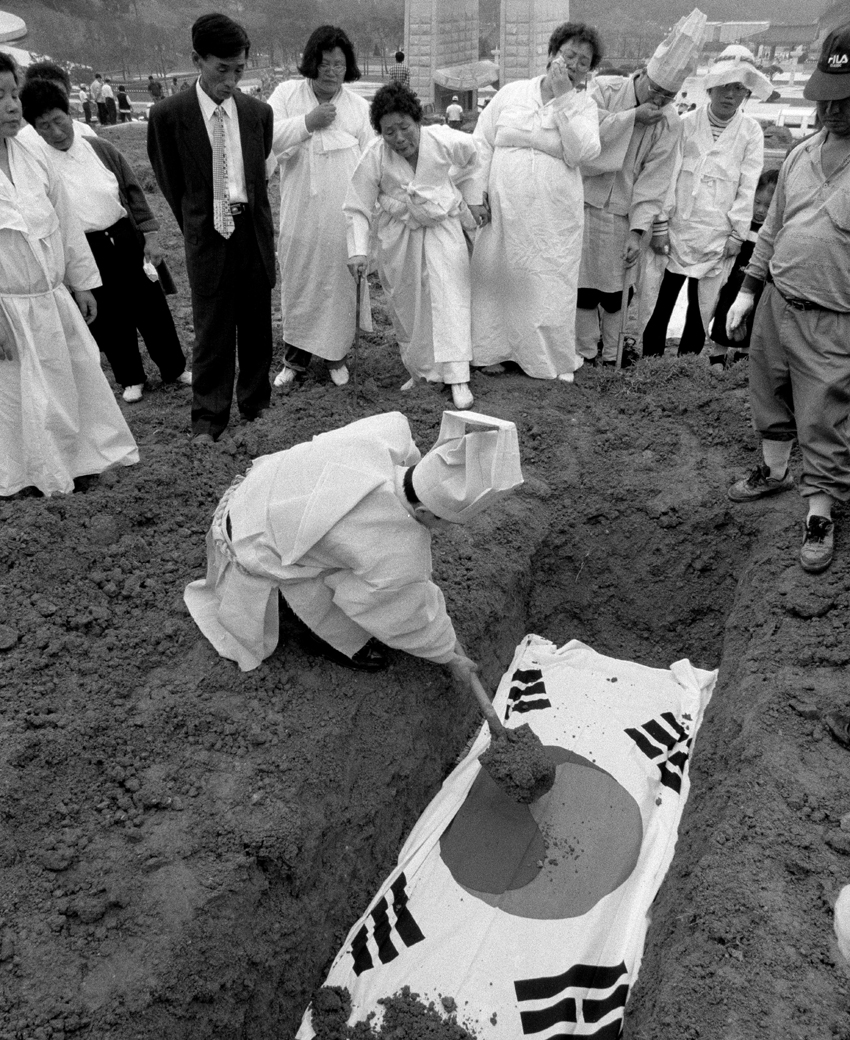 국립5.18민주묘지에 안장되는 희생자의 관에 태극기를 덮고 하관예절을 하고 있는 모습(1997.05)