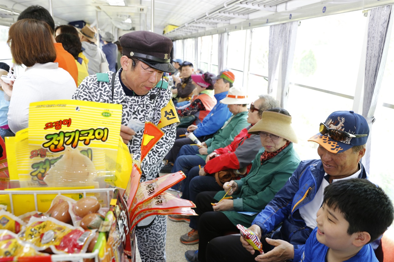 윤재길 씨가 열차 여행객에게 주전부리를 팔며 거스름돈을 주고 있다. 윤 씨는 섬진강 기차마을에서 가정역을 오가는 증기기관열차를 타고 있다.