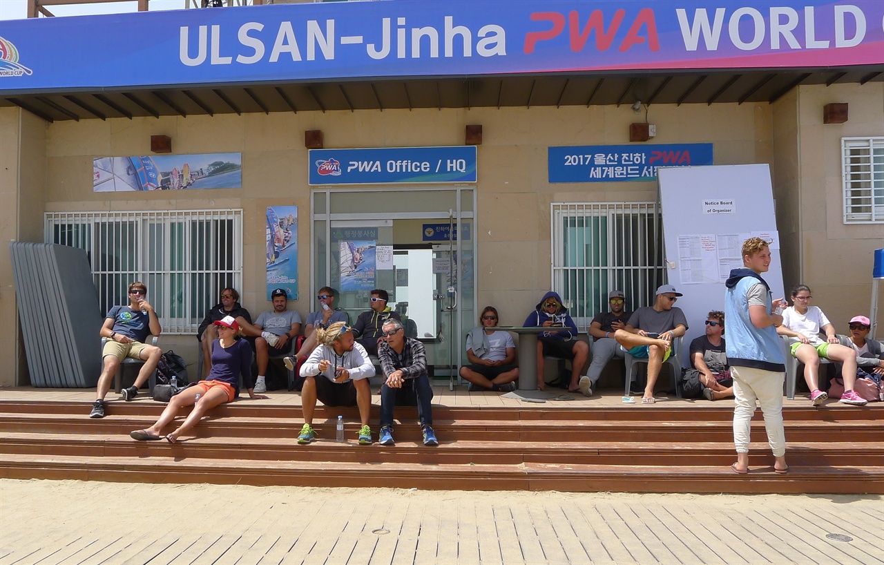  진하PWA세계윈드서핑대회에 참가한 각국 선수들이 운영본부 앞에 모여 앉아 바람이 불기만을 기다리고 있다.