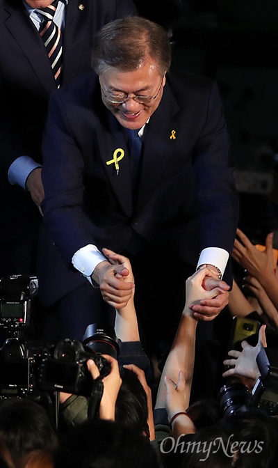 제19대 대통령 당선이 유력한 더불어민주당 문재인 대통령후보가 9일 오후 서울 광화문 세종로공원에서 지지자들의 손을 잡으며 웃고 있다.