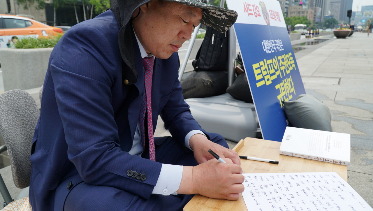 무소속 울산 동구 김종훈 의원이 22일 미대사관 앞에서 1인 시위를 하다  항의서한을 쓰고 있다