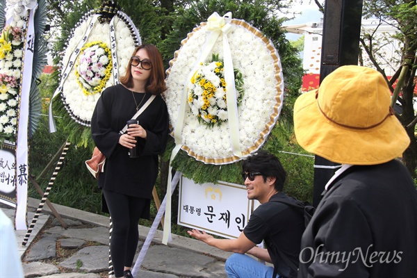 고 노무현 전 대통령 서거 8주기를 맞아, 김해 봉하마을 묘소에 문재인 대통령의 조화가 놓인 가운데 참배객들이 사진을 찍고 있다.