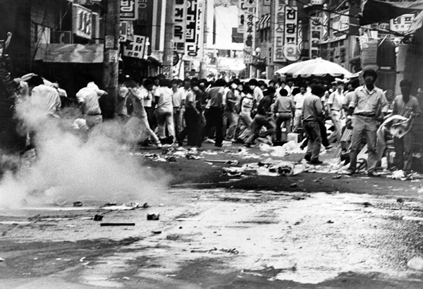 1987년 6월 남대문 시장 한 가운데로 날아온 최루탄을 피해 흩어지는 시민들