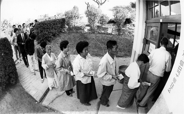 1987년 10월 27일 '헌법 개정안 국민투표'에 참여하려 투표용지와 도장을 들고 일렬로 대기 중인 시민들