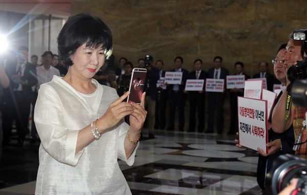 더불어민주당 손혜원 의원이 지난 5월 31일 오후 국회 본회의장에 입장하다 로텐더홀에서 이낙연 국무총리 후보자 인준반대 피켓시위를 하는 자유한국당 의원들을 휴대전화로 촬영하고 있다.