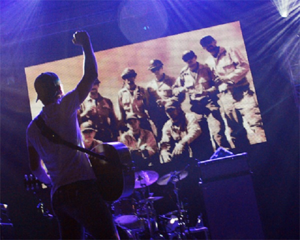 컨트리 가수 디어크스 벤틀리가 애리조나 산불로 순직한 소방관들을 추모하는 공연을 하고 있다. 무대 정면에는 순직한 소방대원들의 사진이 걸려있다. (출처: radio.com)