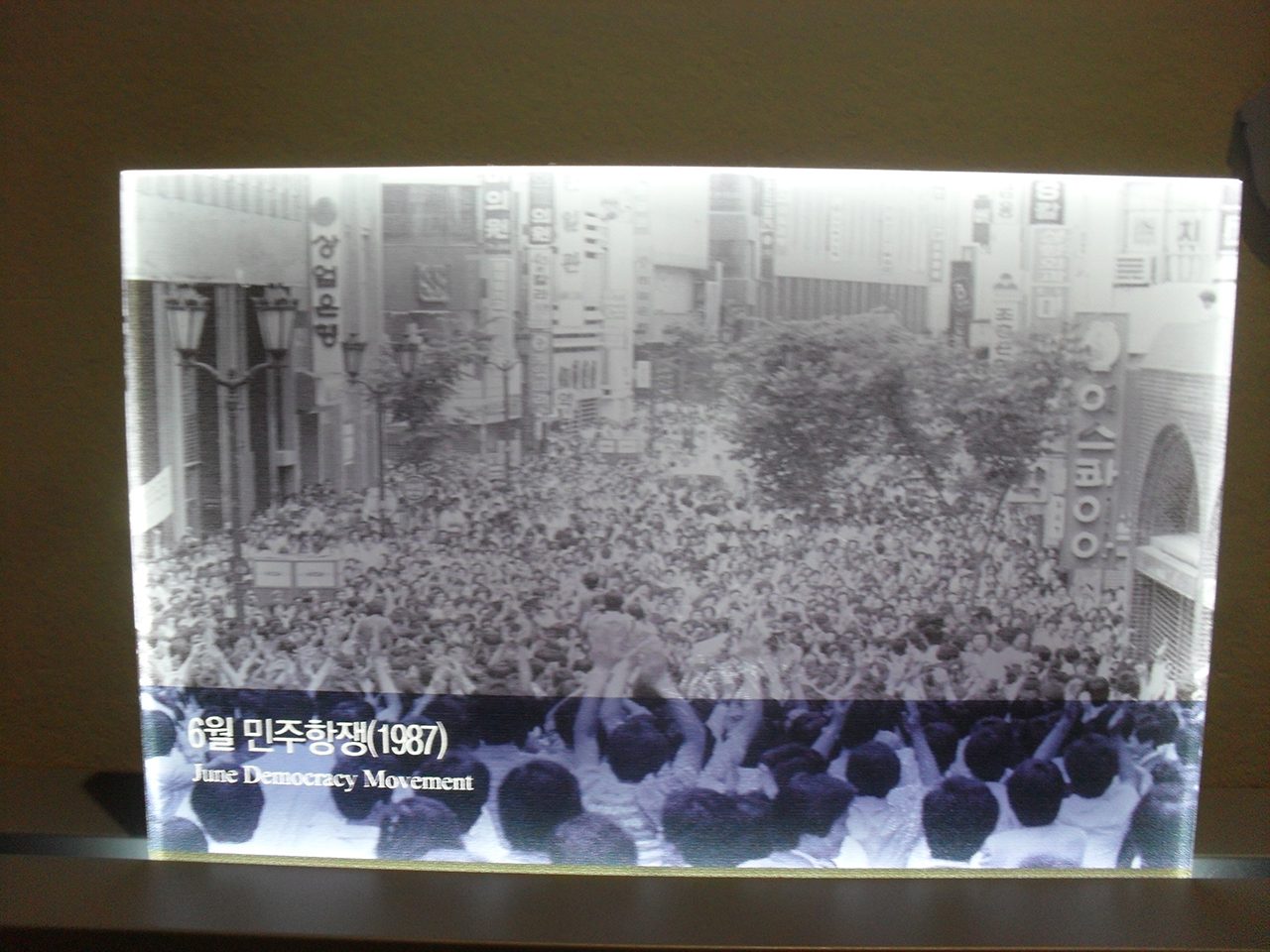 6월항쟁. 길 양쪽에 은행들이 있는 것으로 보아 명동 시위를 찍은 사진 같다. 서울 광화문광장 동편의 대한민국역사박물관에 전시된 사진.