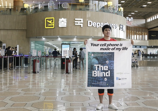 지난 5일 김포공항 출국장 앞에서 메탄올 중독 실명 피해자 김영신씨가 메탄올 중독 실명 사고 영어 백서를 알리는 펼침막을 들고 있다.