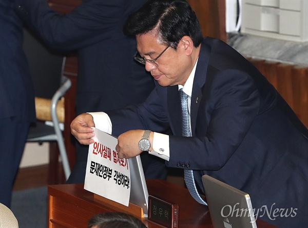 정우택 자유한국당 원내대표가 12일 오후 문재인 대통령의 추경예산안 시정연설을 앞두고 국회 본회의장 자신의 자리에 ‘인사실패 협치포기 문재인정부 각성하라’는 구호가 적힌 종이를 붙이고 있다.