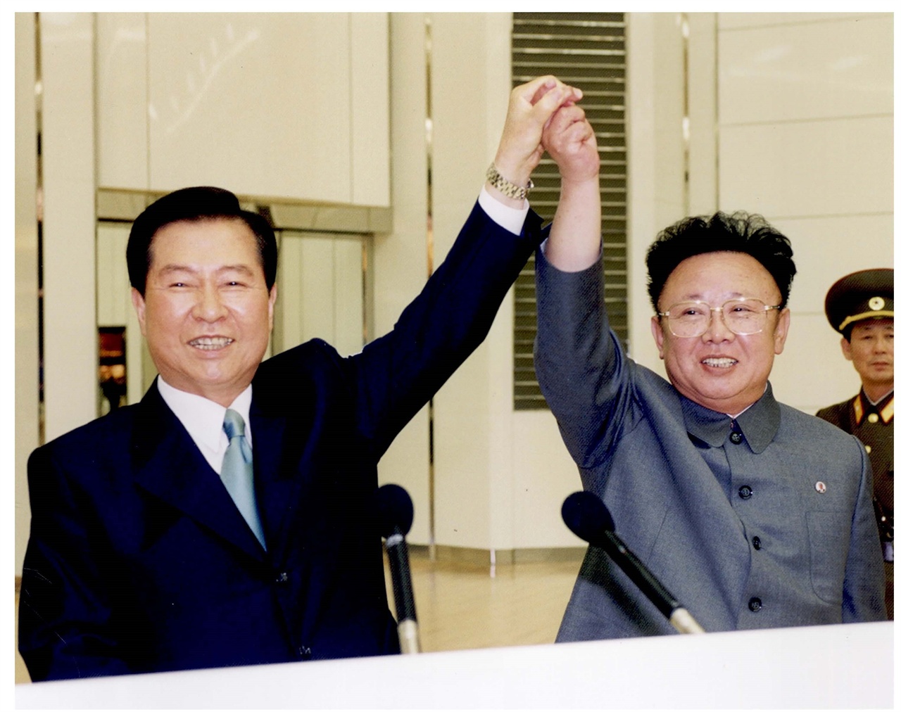 6.15 공동선언 합의를 축하하기 위해 맞잡은 두 손을 올리며 환하게 웃고 있는 김대중 대통령과 김정일 위원장