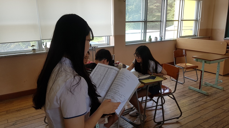홍성여고 학생이 서부중학교 학생들과 함께 영어책을 보면서 수업을 진행하고 하고 있다.