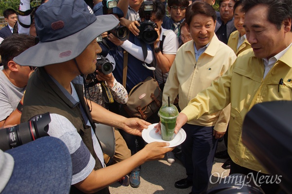 이낙연 국무총리가 21일 오전 낙동강 강정고령보를 방문하자 정수근 대구환경운동연합 생태보존국장이 이 총리에게 녹조가 담긴 물을 건네고 있다.