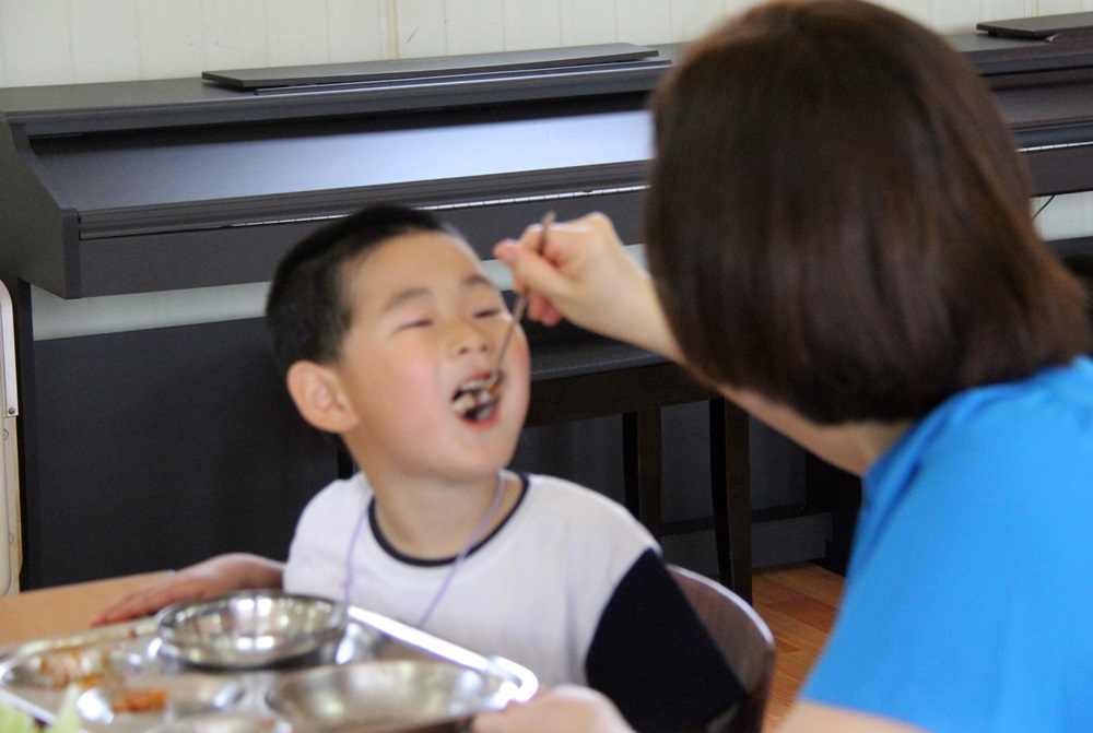 부여 마정초 유치원 교사가 한 원생에게 직접 밥을 떠먹이고 있다.  