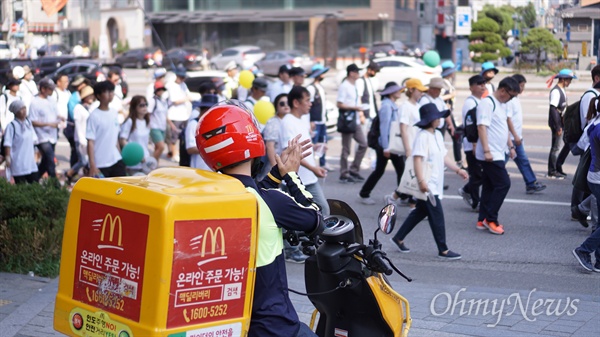  한 맥도날드 라이더(배달원)가 17일 '최저임금 1만 원 실현 걷기대회 만원:런' 참가자들을 향해 박수를 보내고 있다.                   