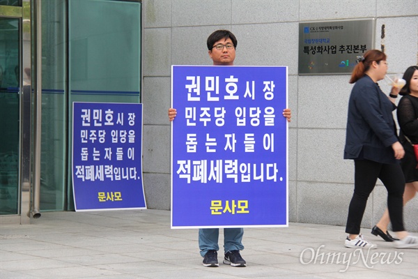 '문사모'(문재인을 사랑하는 사람들의 모임) 회원이 6월 27일 저녁 창원대 종합교육관 앞에서 권민호 거제시장의 입당에 반대하는 손팻말을 들고 서 있다.