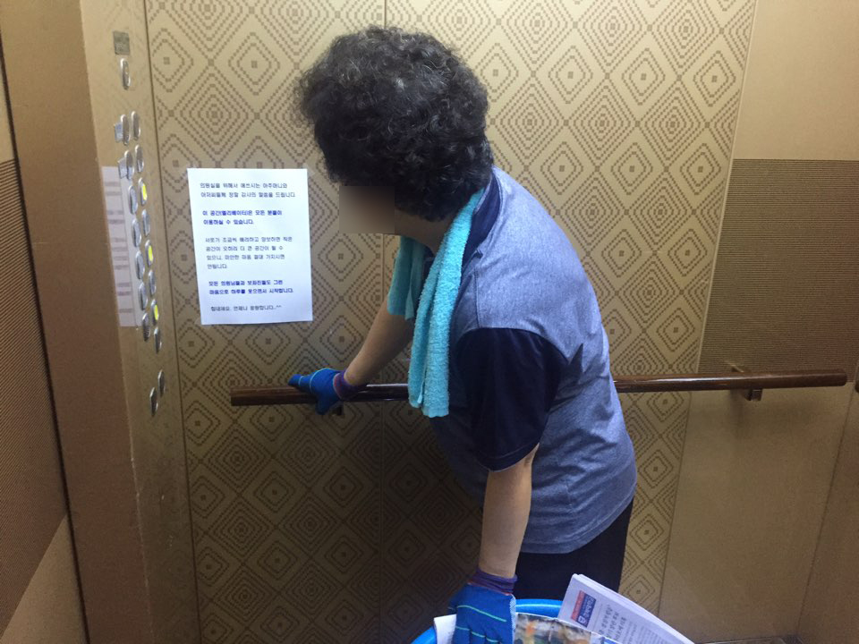 5일 오전 7시께 한 청소노동자가 신문과 우편물을 의원실로 옮기다가 엘리베이터에 붙은 A4 자보를 읽고 있다.
