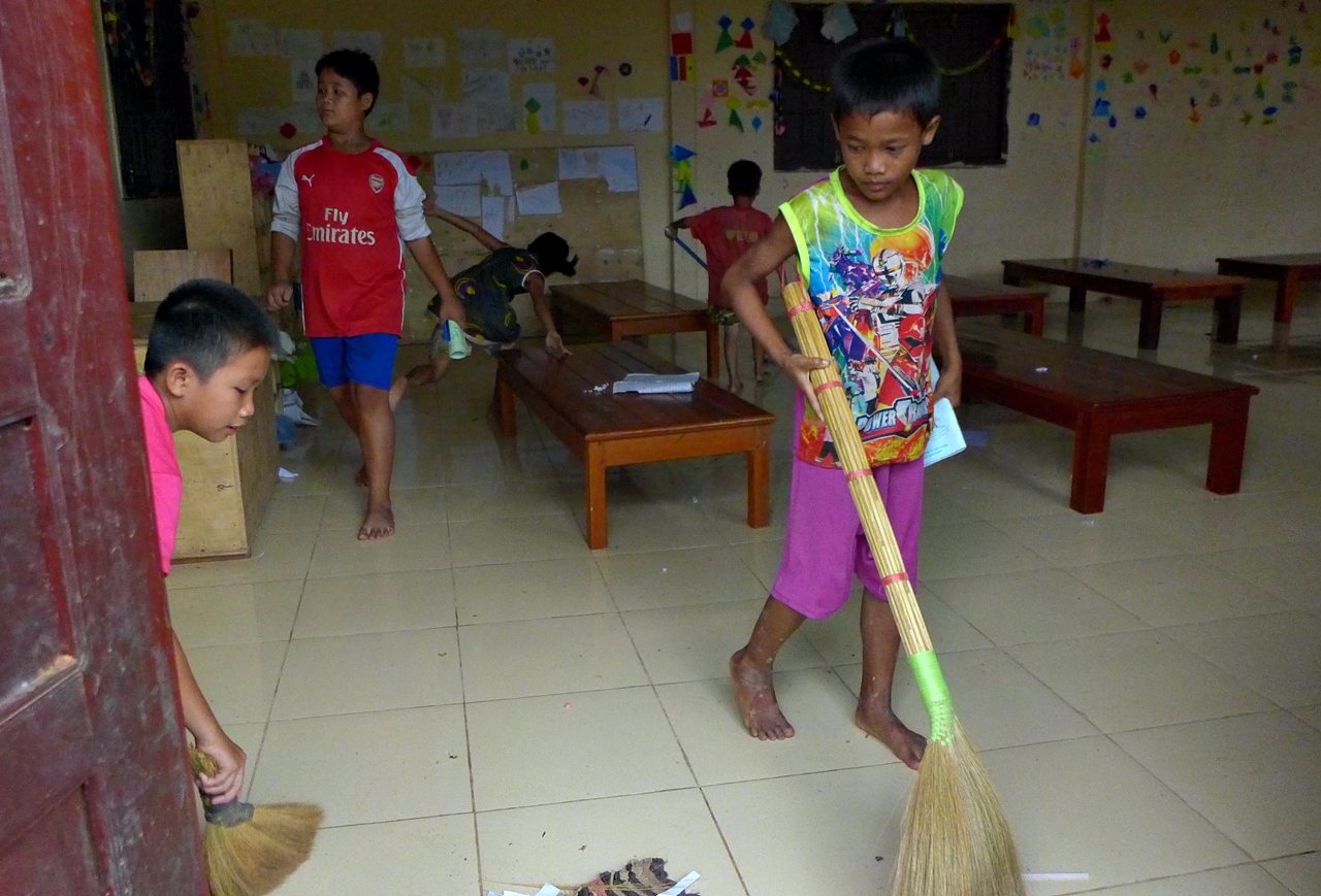 어린 학생들이 자기 키만한 빗자루를 가지고 청소를 한다.