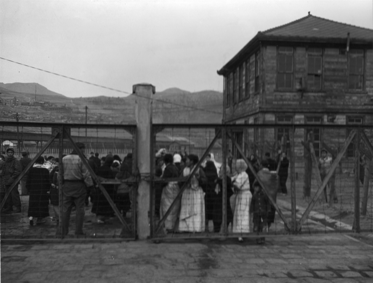  1951. 1. 8. 부산. 먼저 도착한 북한의 함경도 피란민들이 부두 철문 앞에서 뒤따라 올 가족 친지를 하염없이 기다리고 있다.