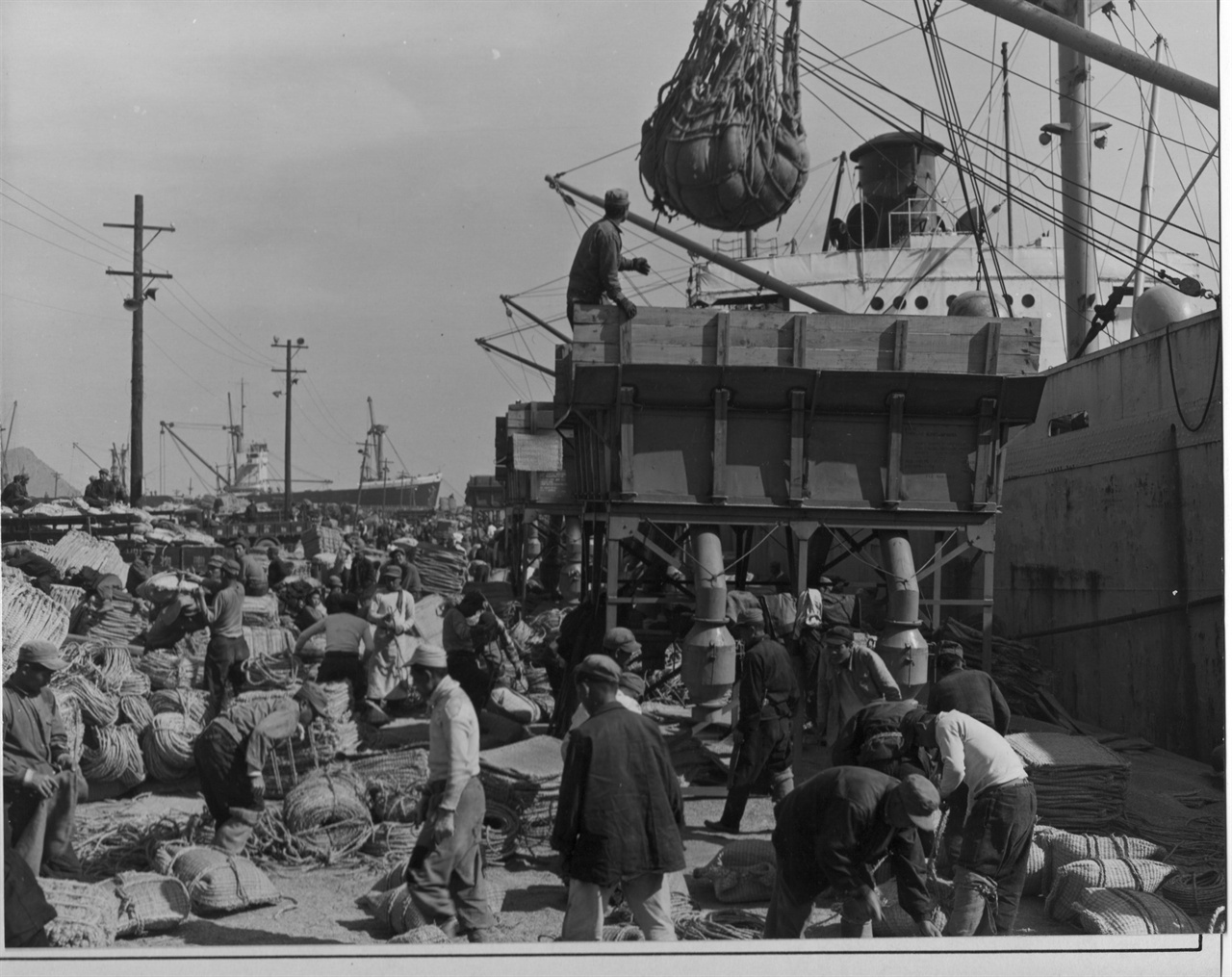  1952. 4. 2. 부산. 부두에서 긴급 구호미로 하역한 양곡을 즉석에서 가마니로 포장하고 있다.