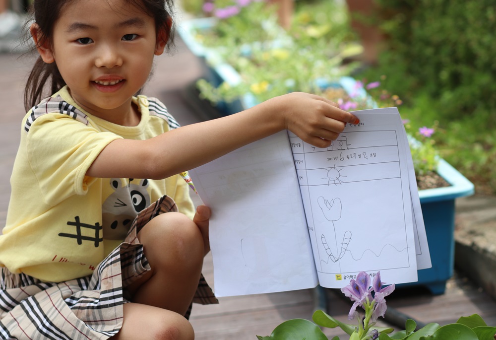 한 아이가 '내 친구 옥잠화를 그렸다'며 자신있게 그림을 펼쳐 보이고 있다.  