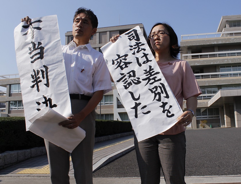 히로시마 지방재판소의 판결 직후, 변호인단이 법원 밖에서 대기 중인 학생들과 기자들 앞에서 '부당판결' '사법은 차별을 용인했다'라는 펼침막을 내보이고 있다.