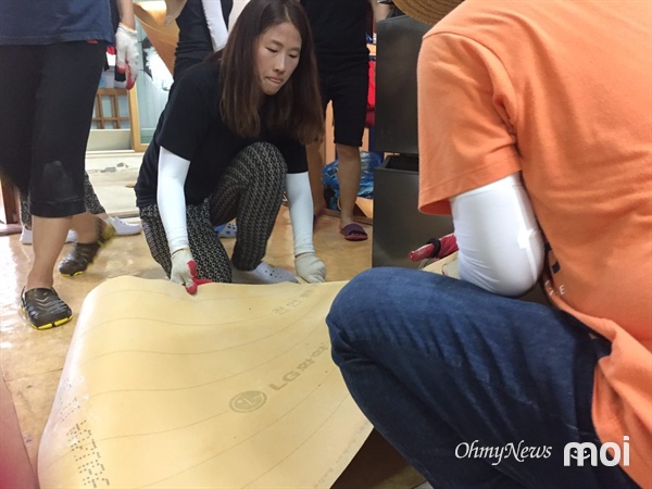 물기가 제거된 바닥에 장판을 깔고 있는 우리미래 김소희 공동대표