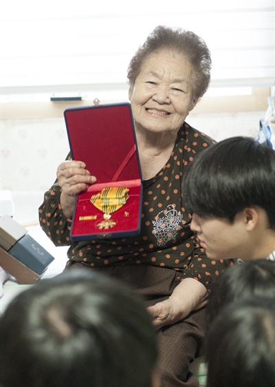 2016년 추석을 맞아 장학생들을 만난 김군자 할머니. 자신의 훈장(동백상)을 보여주고 있다
