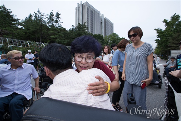 장애인 활동가 박옥순씨가 7월 17일 서울 서초구 서울중앙지방법원 앞에서 자진 노역을 앞두고 기자회견을 마친 후 동료들과 포옹을 하고 있다. 