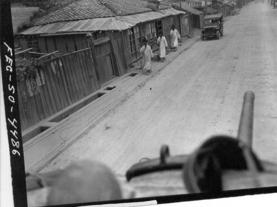  1950. 7. 24. 유엔군 전차가 신작로를 지나가는데 갓을 쓴 노인들은 지팡이를 짚고 유유자적 갓길로 가고 있다.