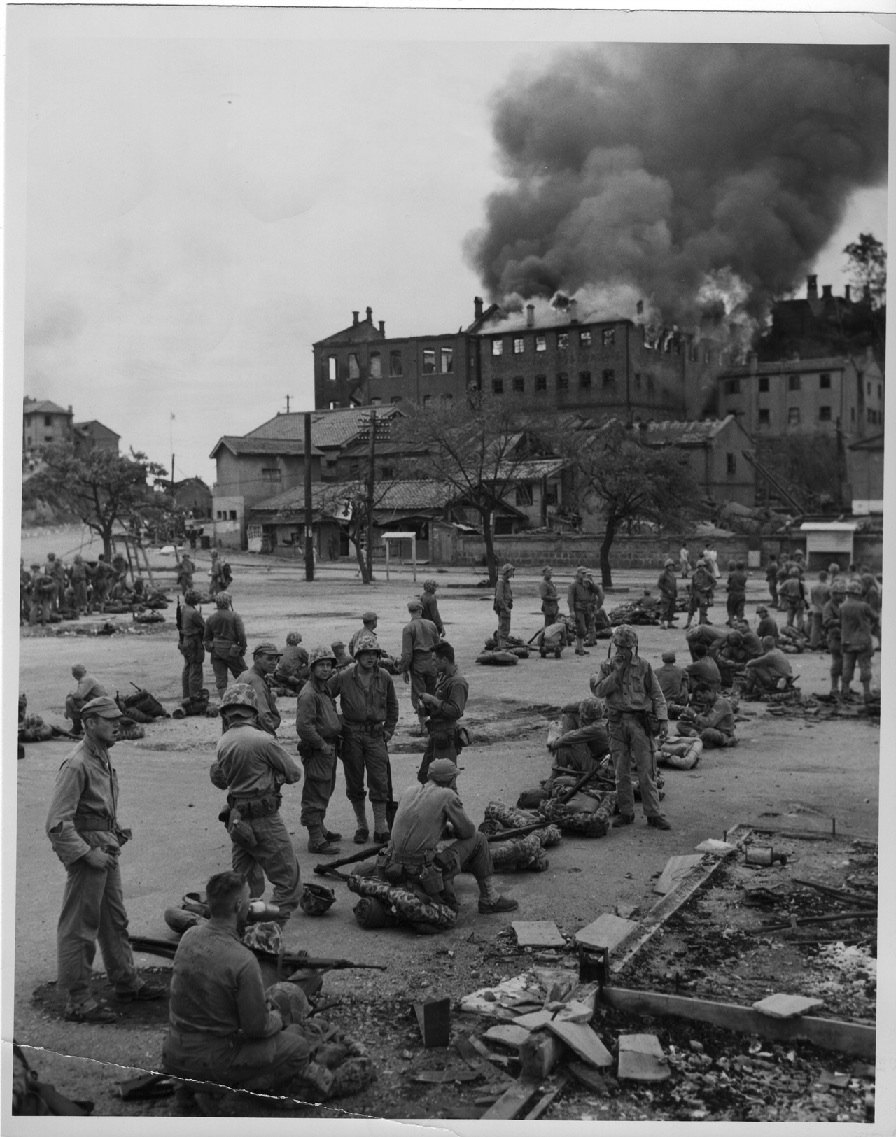   1950. 9. 16.  포격으로 불타고 있는 인천시가지에서 미군들이 잠시 휴식을 취하고 있다.