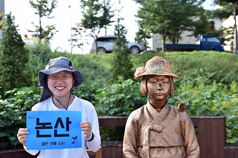 흥사단 평화지기 소녀상 순례길 국토대장정단, 논산 찾아  국토대장정팀원이 소녀상옆에서 열한번째 도시 논산을 들고 기념촬영을 하고 있다.