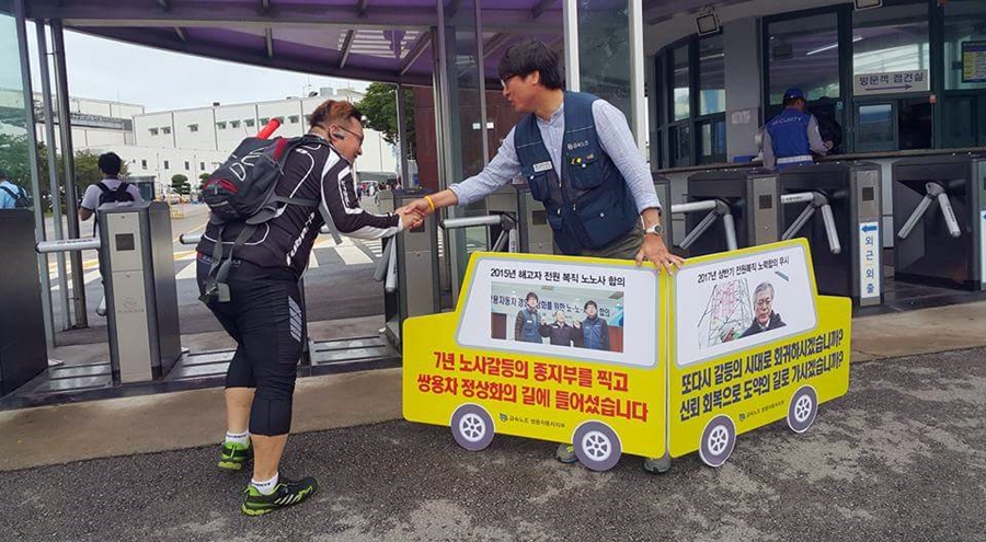 쌍용차 평택공장 앞에서 출근길 1인 시위를 벌이고 있는 김득중 금속노조 쌍용차지부장과 반갑게 인사를 나누고 있는 직원 모습