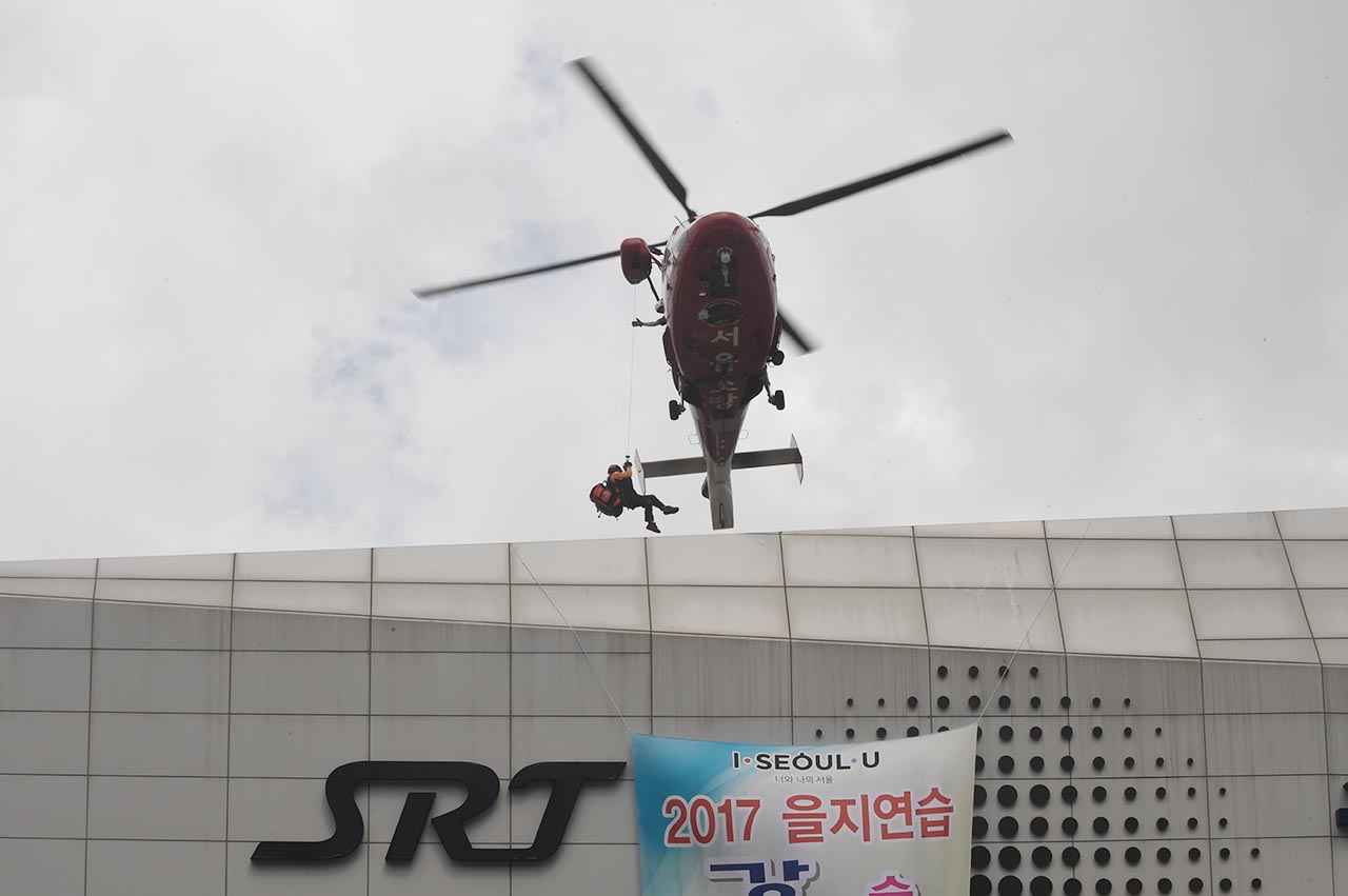 23일 오후 서울 강남구에 위치한 수서고속철도 SRT역에서 적의 장사정포격에 의해 발생한 대형건물 화재진압 및 인명 구조훈련이 실시됐다. 한 소방구조대원이 헬기를 통해 화재가 난 건물 옥상으로 내려가고 있다.