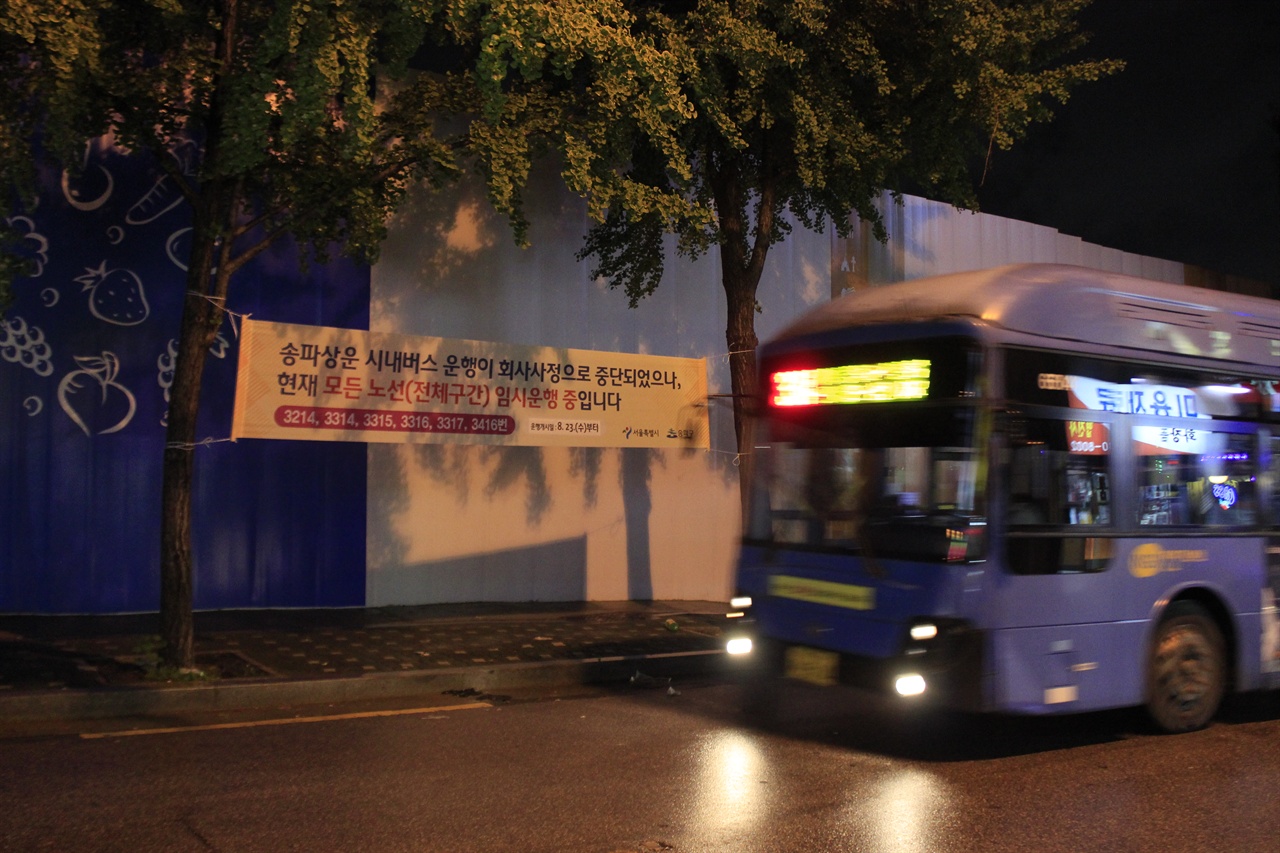 송파상운 운행중단 현수막 앞으로 대체버스가 지나고 있다.