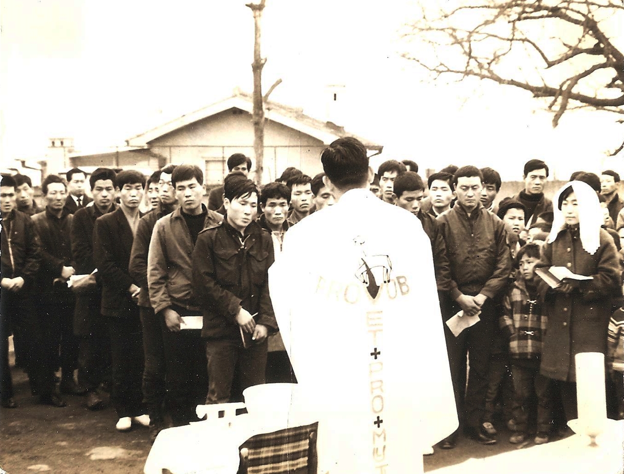 1967년 12월 개미마을 성탄절에 찾아온 김수환 추기경이 전과자 출신의 신자들에게 영세를 주고 있다. 오른 쪽 하얀 미사보를 쓴 사라 김혜경.