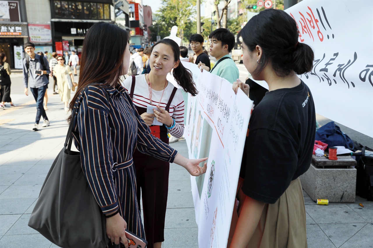 청년월세10만원 운동본부 운동원이 설문에 참여한 시민에게 "조례제정 운동"에 대해 설명하고 있다.
