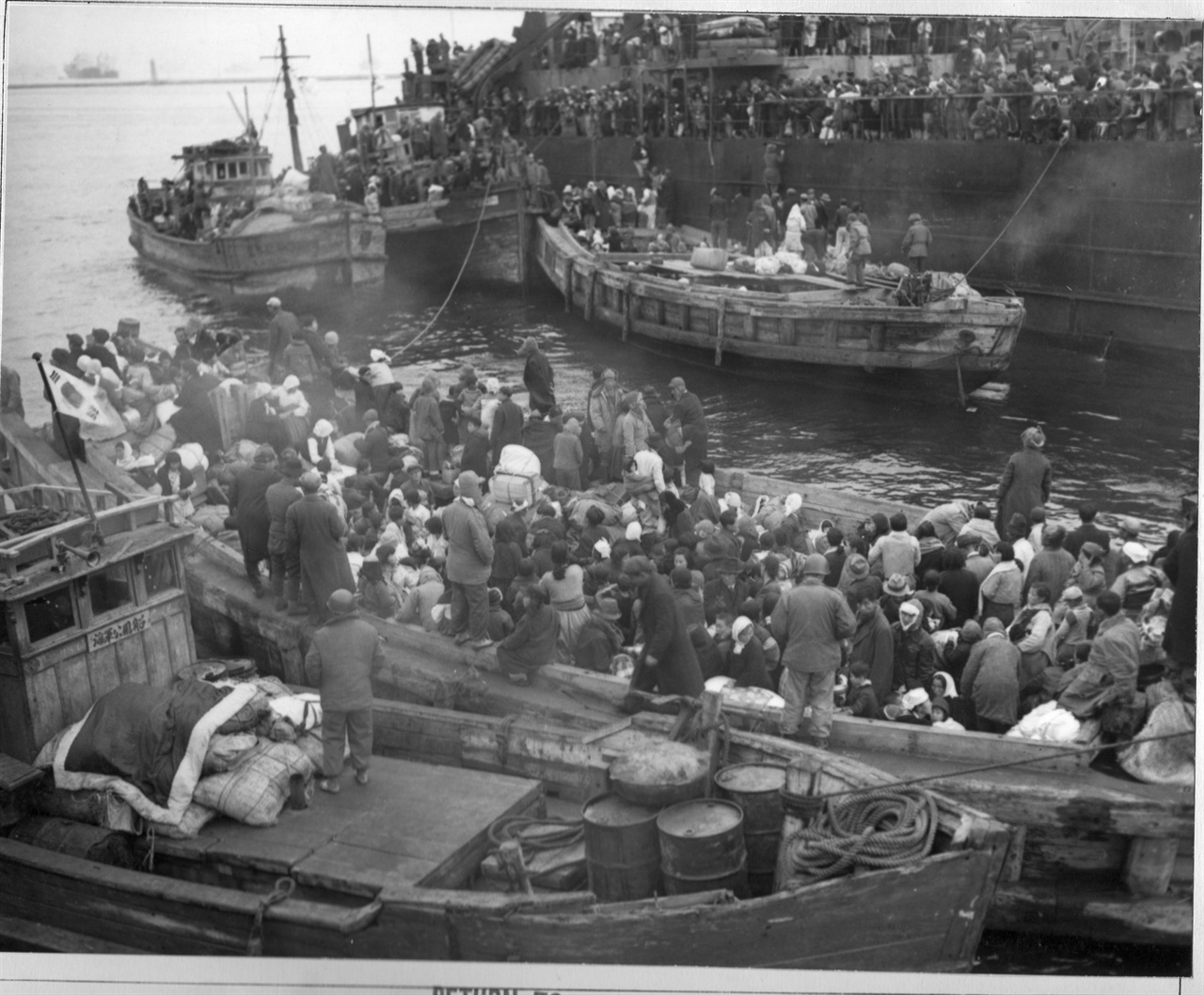  1950. 12. 19. 피란민들이 흥남 항에 정박 중인 피란민 수송선에 타고자 목선을 타고 접근하고 있다. 