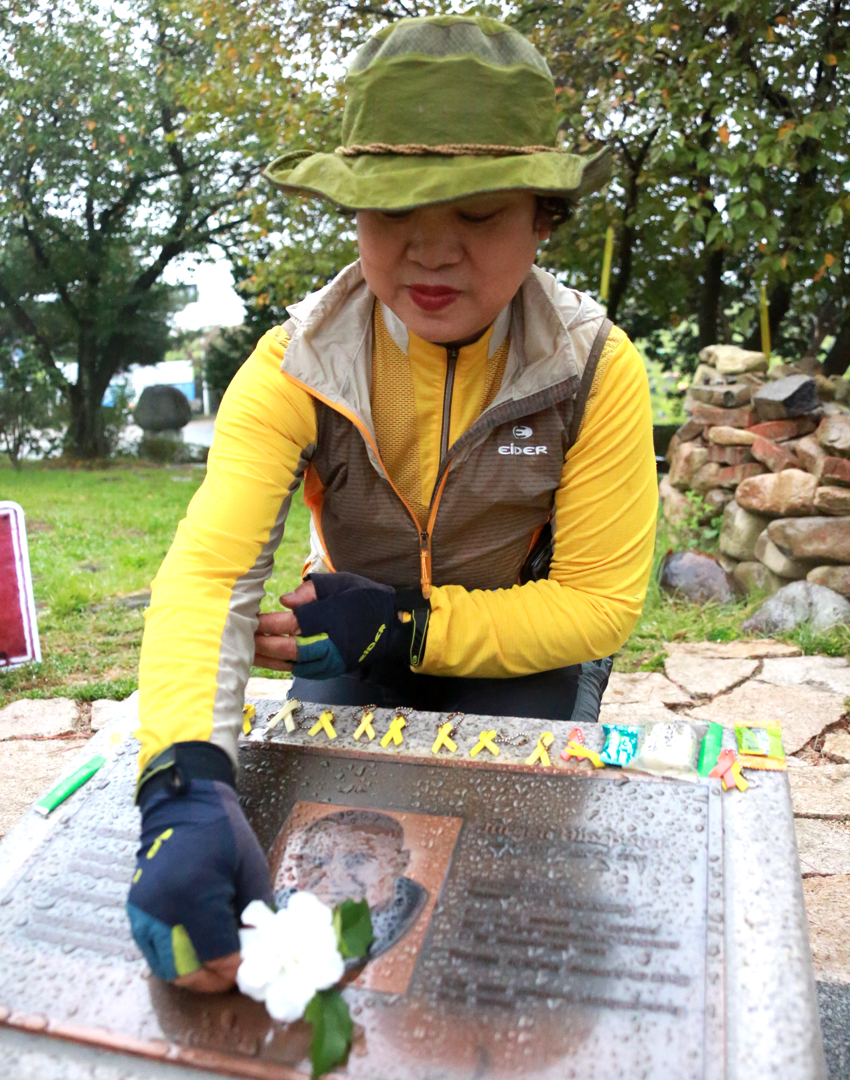 5.18택시 탑승객 조민자씨가 힌츠페터 묘비에 무궁화꽃 한송이를 헌화하는 모습
