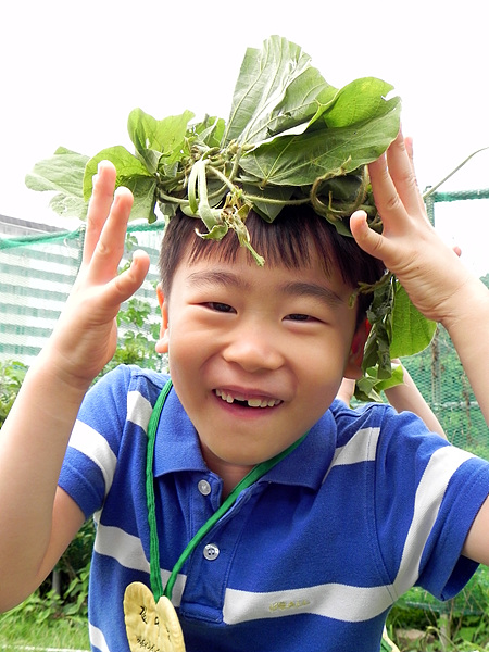 숲학교에 온 아이가 넝쿨을 뒤집어 쓴 채 천진난만하게 웃고 있다