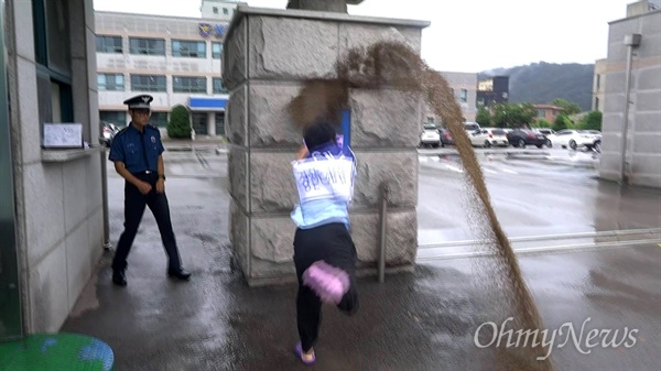 환경활동가 박성수(둥글이)씨가 11일 오전 경북 성주경찰서 앞에서 경찰의 강제진압을 비난하는 퍼포먼스로 개사료를 뿌리고 있다.