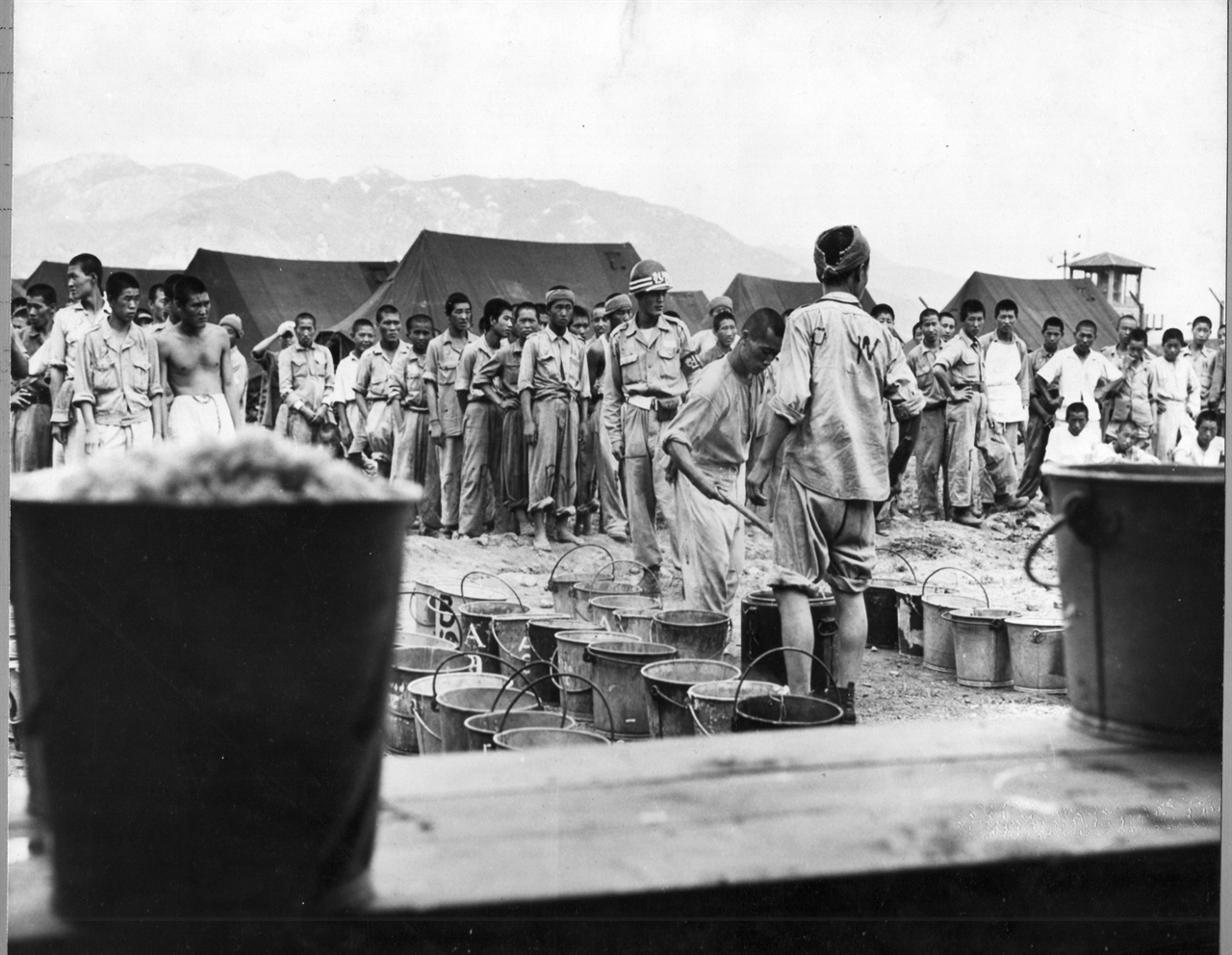  1951. 9. 부산. 포로수용소에서 식사시간 포로(P. W) 취사병이 동료들에게 배식을 하고 있다.