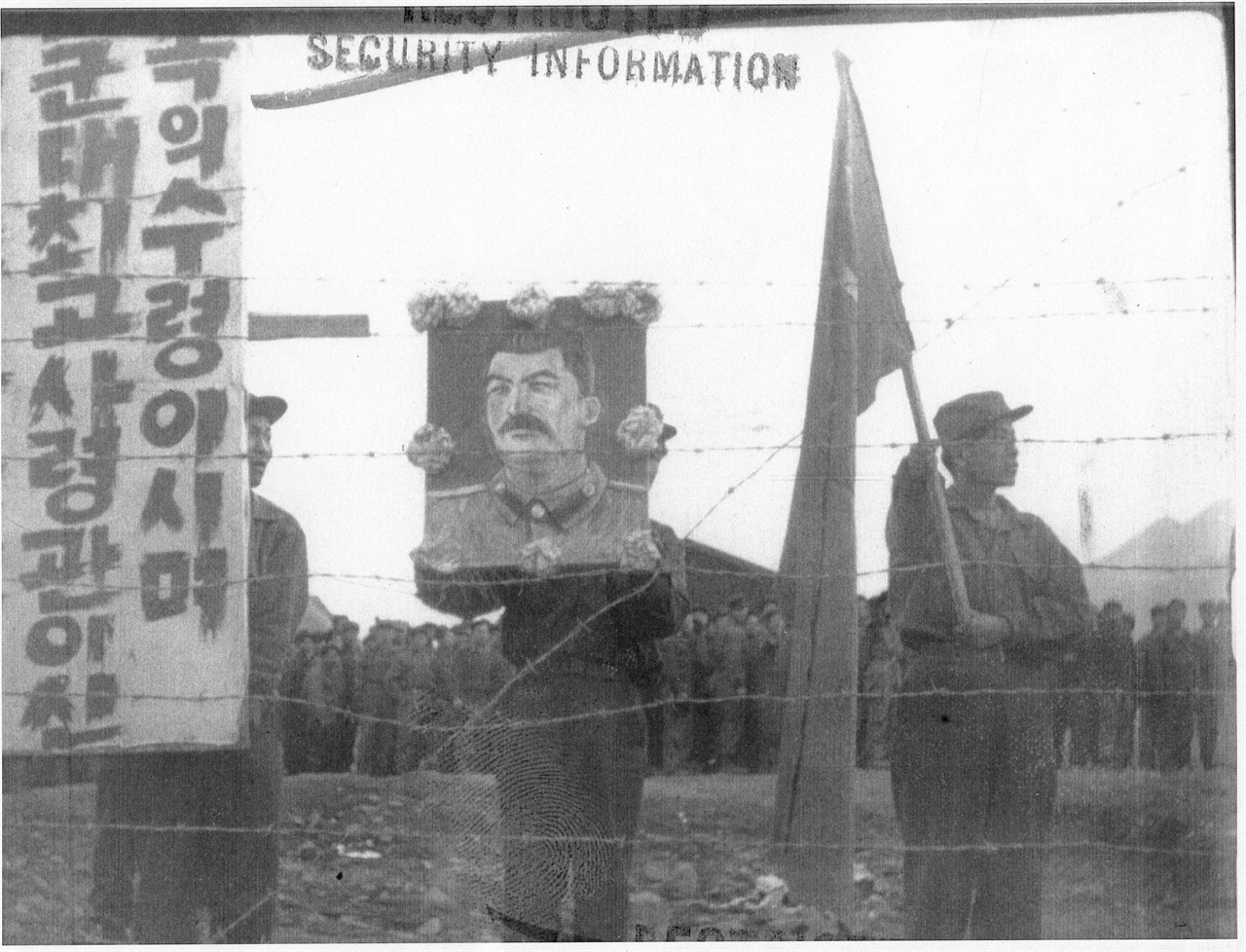  1952. 2. 8. 거제도, 포로수용소의 포로들이 스탈린 초상과 인공기를 들고 철조망 안에서 시위하고 있다.