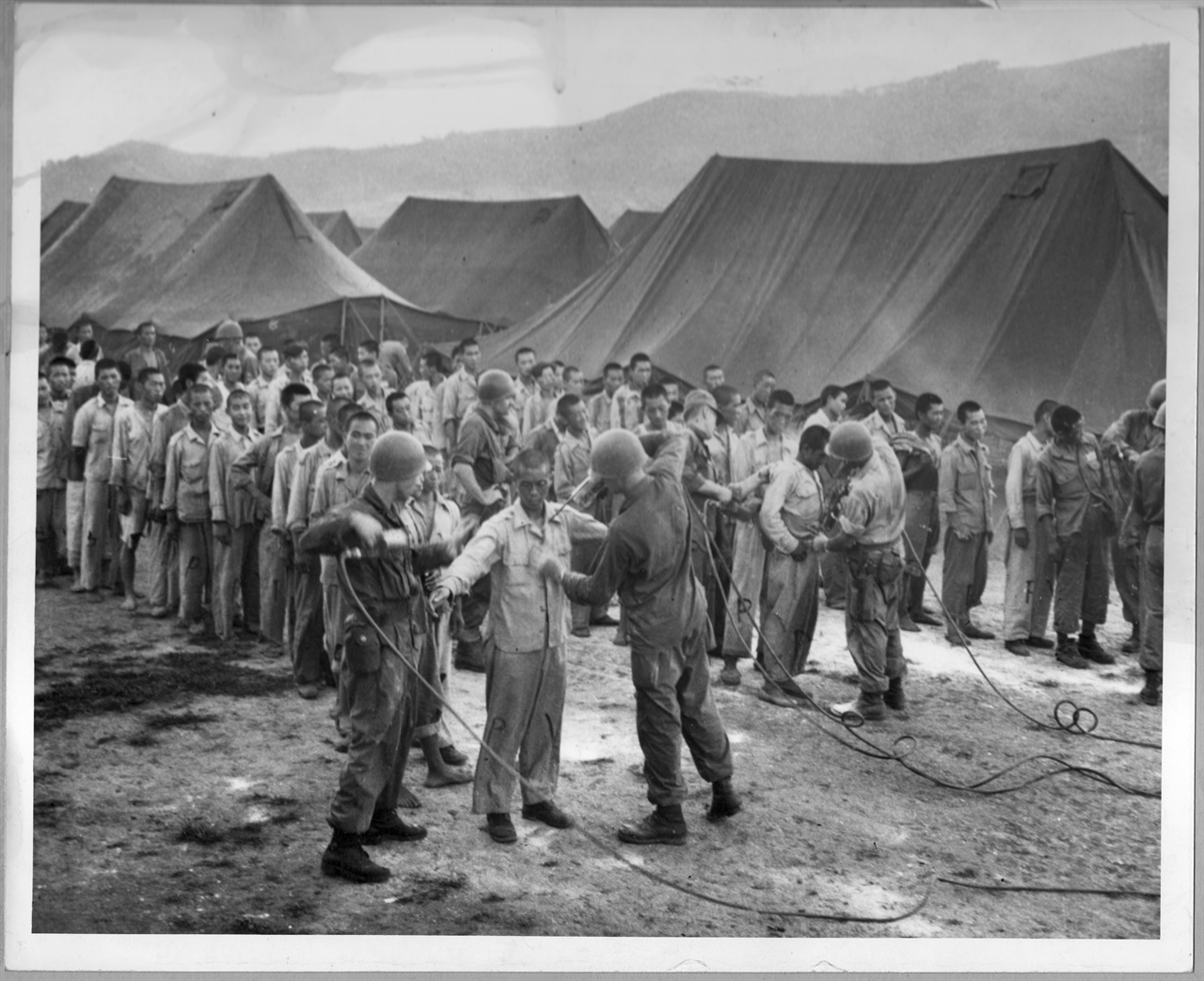  1952. 5. 거제포로수용소 기간병들이 포로들에게 몸에 이를 구충하고자 DDT를 살포하고 있다.