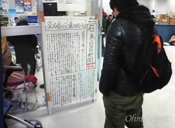 2011년 동일본대지진 당시 한 주민이 <이시노마키히비신문>을 보고 있다. 쓰나미로 윤전기가 침수되는 피해를 입은 신문사는 손으로 쓴 벽보 신문을 만들어 대피소에 부착했다. 
