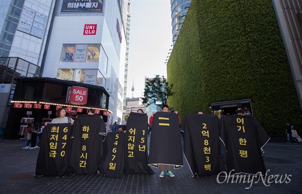   세계주거의 날을 3일 앞 둔 29일 오후 서울 중구 명동역 인근 삼영빌딩 앞에서 한평(3.3제곱미터) 크기의 고시원 평면도 위에 생활하는 모습의 ‘한평괴담 플래시몹’이 펼쳐지고 있다. 화장품 회사인 네이처리퍼블릭이 입주해 있는 삼영빌딩은 국토교통부 2017년 전국개별공시지가로 3.3제곱미터(한평)당 2억8380만원으로 145억 5980만원에 달한다. 이 가격은 공시지가 14년째 1위이다. 
