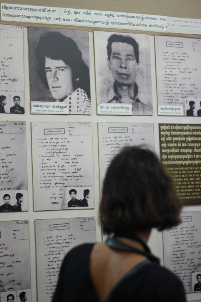 1970년대 내전 당시 크메르루즈 공산게릴라군에 의해 희생된 서양인의 흑백사진을 한 여행객이 지켜보고 있다.