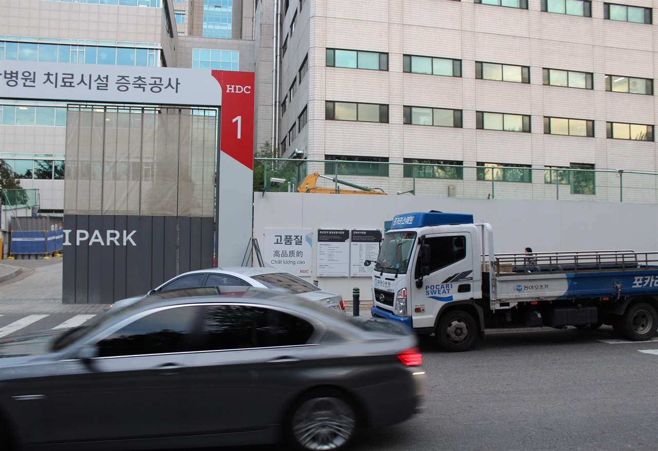 약국호객차량이 늘어선 인근에 병원의 치료시설증축공사가 이루어지고 있다.