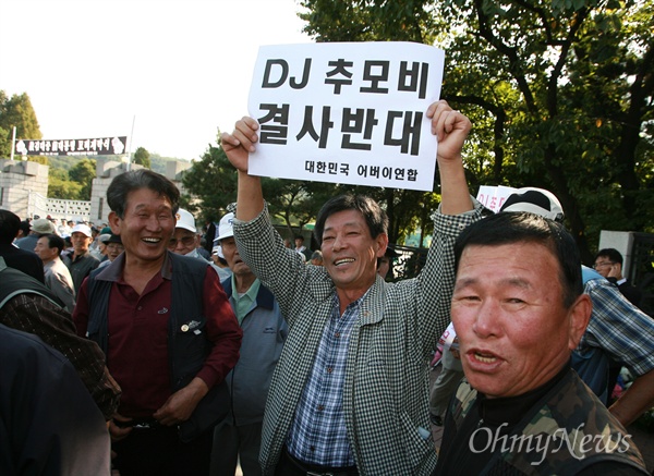 대한민국 어버이연합 회원이 'DJ 추모비 결사반대'가 적힌 종이를 들고 있다.