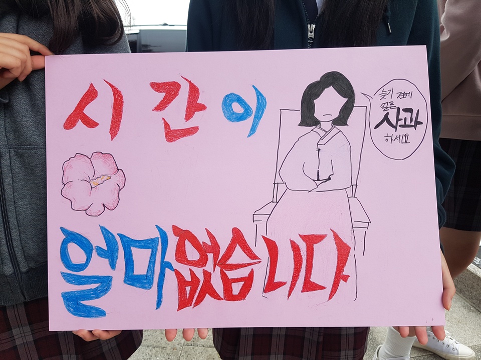 '시간이 얼마 없습니다. 늦기 전에 얼른 사과하세요'라고 씌여진 손팻말을 들고 일본의 사과를 요구하는 학생들 모습