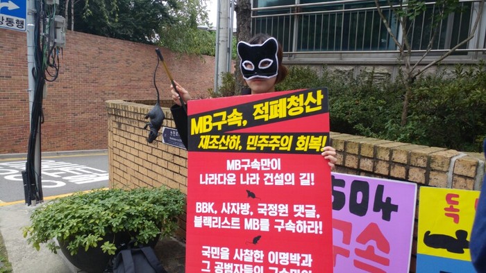 1인 시위에 나선 여성 특공대원이 고양이 마스크를 쓰고 모형 쥐를 든채 시위를 펼치고 있다.